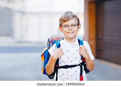 Happy little kid boy with glasses and backpack or satchel. Schoolkid on the way to school. Portrait of healthy adorable child outdoors. Student, pupil, back to school. Elementary school age