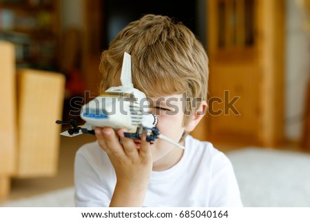 Happy little kid boy playing with space shuttle toy. Cute child in having fun in the morning before school. Closeup of face and old toy