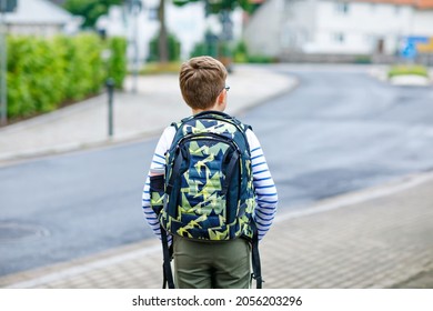 Happy little kid boy with satchel and eyeglasses. Schoolkid wearing glasses on the way to middle or high school. Excited child outdoors on school yard. Back to school.