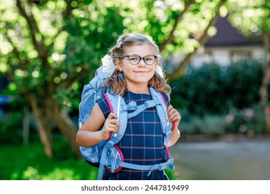 Happy little kid girl with eye glasses with backpack or satchel and big school bag on the first day of school. Healthy adorable child outdoors. Back to school - Powered by Shutterstock