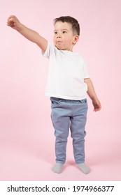 Happy Little Kid Imitate Super Hero. Boy In A Hero Pose On Pink Background. High Quality Photo