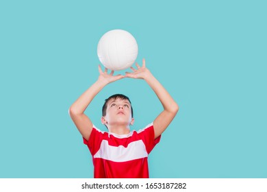 Happy little kid in a red shirt with a ball for volleyball. Physical, sport.