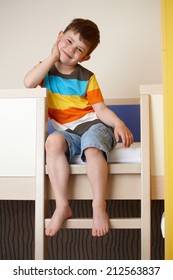 Happy little kid sitting on bunk bed, smiling.