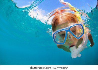 Happy Little Kid In Snorkeling Mask And Wetsuit Jump And Dive Underwater In Coral Reef Sea Lagoon. Family Travel Lifestyle In Summer Adventure Camp. Swimming Activities On Beach Vacation With Child.