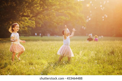 Happy Little Kids Blowing Soap Bubbles In Summer Park