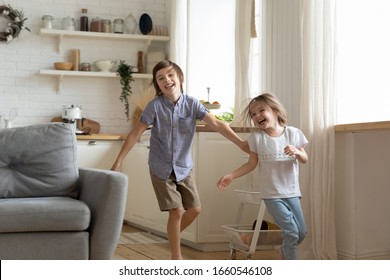 Happy little preschooler siblings have fun run around kitchen together, smiling small brother and sister feel playful racing playing engaged in funny childish activity at home, entertainment concept - Powered by Shutterstock