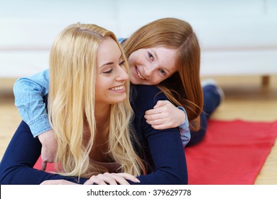 Happy Little Red Haired Girl Climbing Over The Shoulders Of Smiling Mother Looking Back At Her