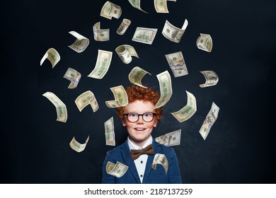 Happy Little Redhead Kid Boy Standing Under Money Rain Against Blackboard Wall Background