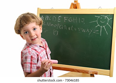 Happy little school boy writing on the blackboard