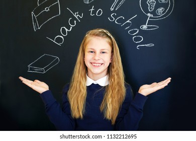 Happy little  school girl near school blackboard
