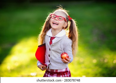 Happy little schoolgirl with lunch, book and pencils. Back to school outdoor - Powered by Shutterstock