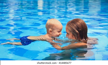 Happy Little Sports Man Has Swimming Lesson With Mother - Active Baby Boy Swim With Fun In Woman Hands In Blue Pool. Family Lifestyle, Summer Children Water Activity And Fitness With Parents.