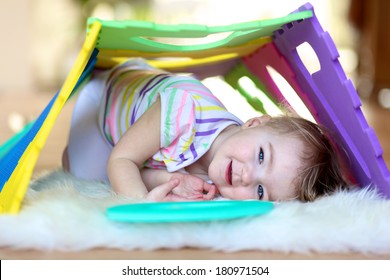 Happy little toddler girl playing hide and seek and learning numbers with colorful soft puzzles