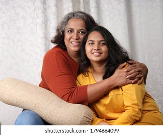 Happy Looking Young Indian Girl With Her Mother Sitting On A Couch Or Sofa. Concept Mother's Day