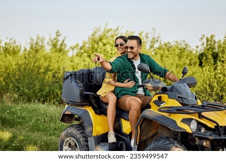 A happy love couple having an adventure while driving a rental quad bike off-road, enjoying the beautiful nature.