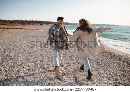Happy love couple running at sea shore wear casual coat and denim pants at beach outdoor. Carefree lifestyle concept. 