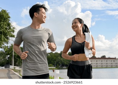 A happy, lovely Asian couple in sportswear enjoys running together in a park in the morning. outdoor activity and healthy lifestyles concepts - Powered by Shutterstock