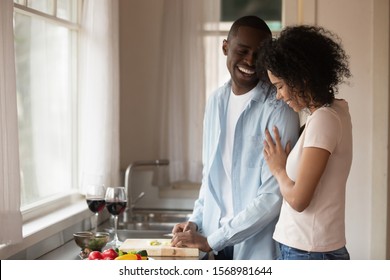 Happy loving african American couple enjoy weekend at home cooking in kitchen together, smiling caring biracial husband and wife have fun rest indoors prepare food spend romantic domestic date - Powered by Shutterstock