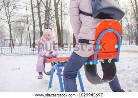 Happy loving caucasian family of mother father and daughter play, having fun in winter snowy park. Cute little girl playing