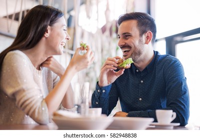 Happy loving couple enjoying breakfast in a cafe. Love, dating, food, lifestyle - Shutterstock ID 582948838