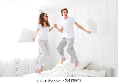 Happy loving couple jumping and having fun in bed