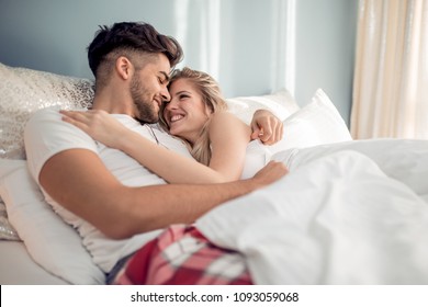 Happy loving couple lying together on bed at home. - Powered by Shutterstock