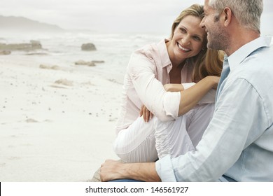 Happy Loving Couple Sitting On Beach