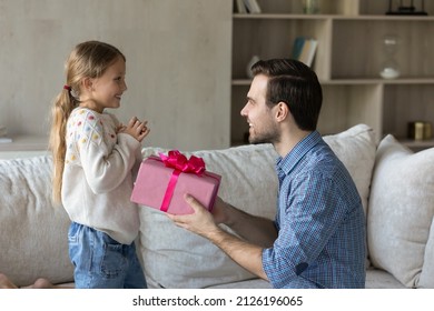 Happy Loving Dad Giving Surprise Gift To Excited Little Daughter Kid, Holding Pink Wrap, Congratulating Girl On Birthday. Overjoyed Child Getting Present From Beloved Daddy, Feeling Joy, Happiness