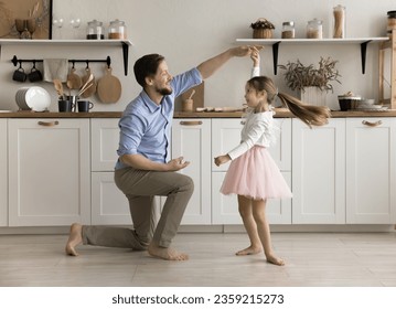 Happy loving daddy dancing with little princess daughter kid, holding hand of girl wearing pink ballet skirt, spinning around with flying hair, training choreograpgy, playing active game - Powered by Shutterstock