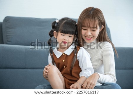 Happy loving family. Asian mother and her daughter child girl playing in living room. while using laptop.
