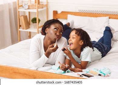 Happy Loving Family. Black Mother And Daughter Doing Make Up, Having Fun, Lying On Bed, Copy Space