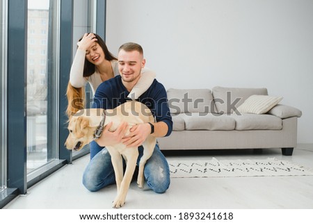 Happy Loving Family Concept. Portrait of beautiful couple with dog sitting on the floor in modern apartment