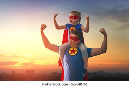 Happy loving family. Dad and his daughter playing outdoors. Daddy and child girl in an Superhero's costumes. Concept of Father's day.