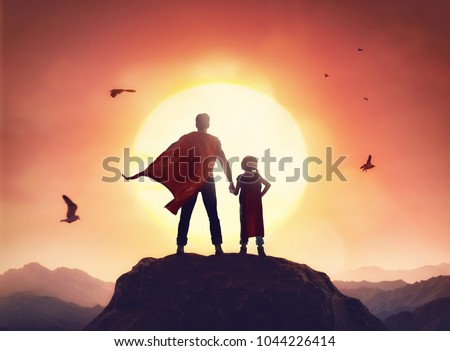 Happy loving family. Father and his daughter playing outdoors. Daddy and his child girl in an Superhero's costumes.