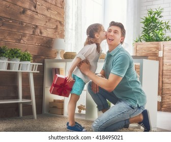 Happy Loving Family And Father's Day. Father And His Daughter. Cute Child Girl Kisses Dad And Gives Him A Gift.