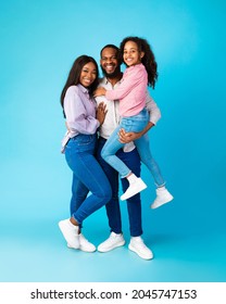 Happy Loving Family. Full Body Length Of Cheerful African American Man Holding Excited Daughter On Hands, Looking And Posing At Camera, Having Fun, Hugging Lady Isolated Over Blue Studio Background