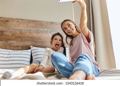 Happy Loving Family. Mother And Child Girl Playing, Having Fun, Taking Photo, Showing Tongue, Smiling Brightly, Morning Time In Bedroom, Shot From Below, Family Portrait