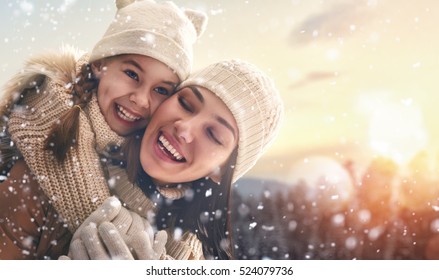 Happy Loving Family! Mother And Child Girl Having Fun, Playing And Laughing On Snowy Winter Walk In Nature. Frost Winter Season.