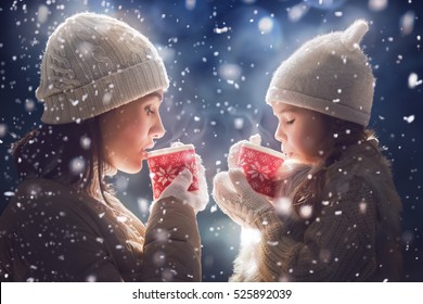 Happy loving family! Mother and child girl drinking tea on snowy winter walk in nature. Frost winter season.