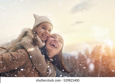 Happy Loving Family! Mother And Child Girl Having Fun, Playing And Laughing On Snowy Winter Walk In Nature. Frost Winter Season.