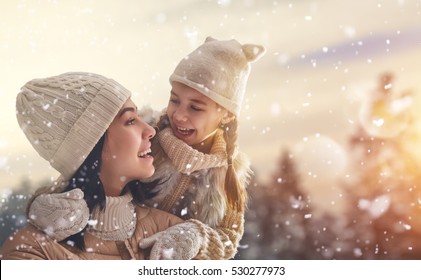 Happy Loving Family! Mother And Child Girl Having Fun, Playing And Laughing On Snowy Winter Walk In Nature. Frost Winter Season.