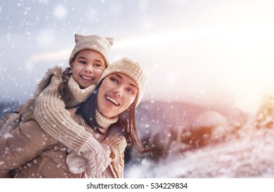 Happy Loving Family! Mother And Child Girl Having Fun, Playing And Laughing On Snowy Winter Walk In Nature. Frost Winter Season.