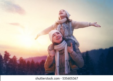 Happy Loving Family! Mother And Child Girl Having Fun, Playing And Laughing On Snowy Winter Walk In Nature. Frost Winter Season. 