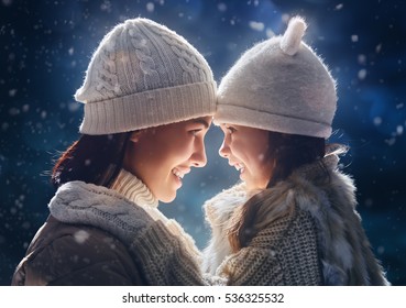 Happy Loving Family! Mother And Child Girl Having Fun, Playing And Laughing On Snowy Winter Walk In Nature. Frost Winter Season. 