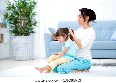 Happy loving family. Mother is combing her daughter's hair sitting on the carpet on the floor in the room - Powered by Shutterstock