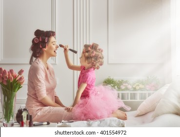 Happy loving family. Mother and daughter are doing hair and having fun. Mother and daughter doing your makeup sitting on the bed in the bedroom. - Shutterstock ID 401554972