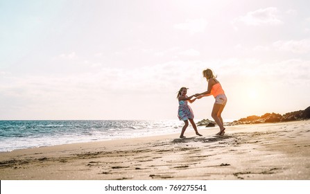 Happy Loving Family Mother And Daughter Having Fun On The Beach At Sunset - Mum Playing With Her Kid Next Sea In Holidays - Parent, Vacation, Family Lifestyle Concept