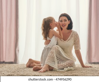 Happy Loving Family. Mother And Her Daughter Child Girl Playing And Hugging. Daughter Whispering To Mom A Secret.