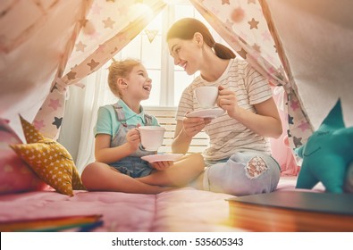 Happy loving family. Mother and her daughter girl play tea-party and drink tea from cups in children room. Funny mom and lovely child having fun indoors. - Powered by Shutterstock