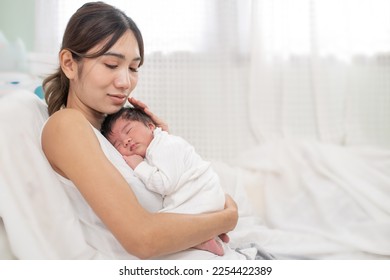 happy loving family. mother playing with her baby hugging in the bedroom , portrait of asian mother playing with newborn baby, health care family love together. asian girl lifestyle.